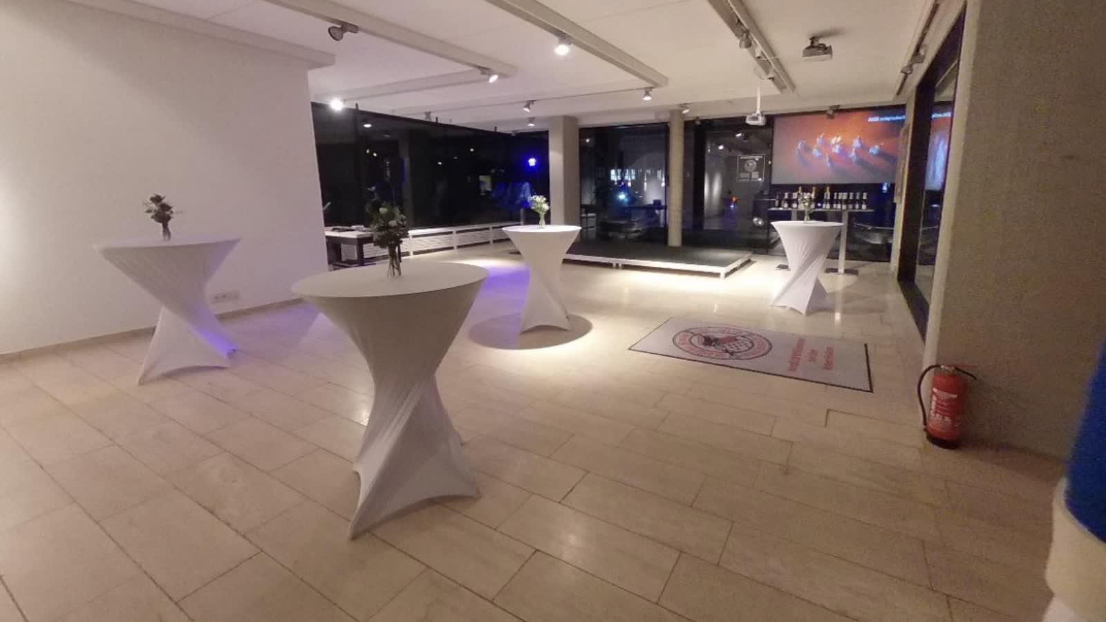 Derselbe Raum am Abend, fertig aufgebaut mit beleuchteten Stehtischen